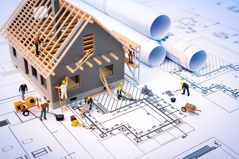 building plans and blueprints with a model of a house on top and workers surrounding it.